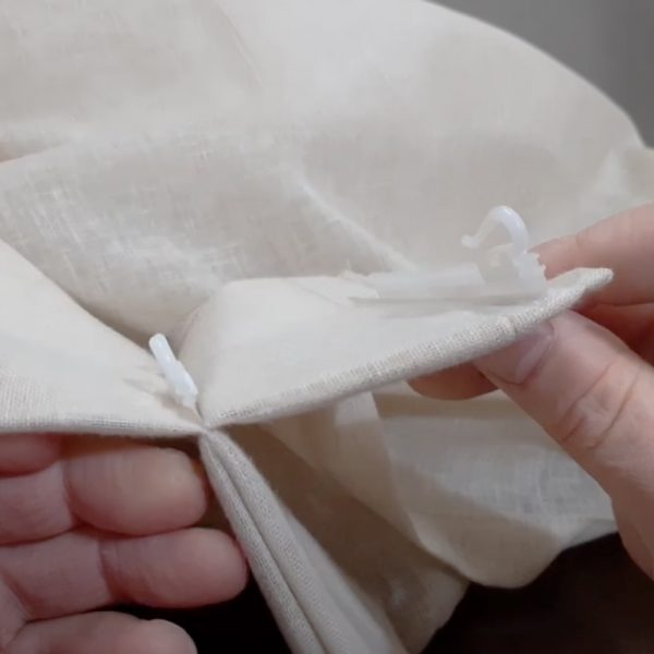 Close-up of pinch-pleated drapery with microflex drapery hooks sewn into it.