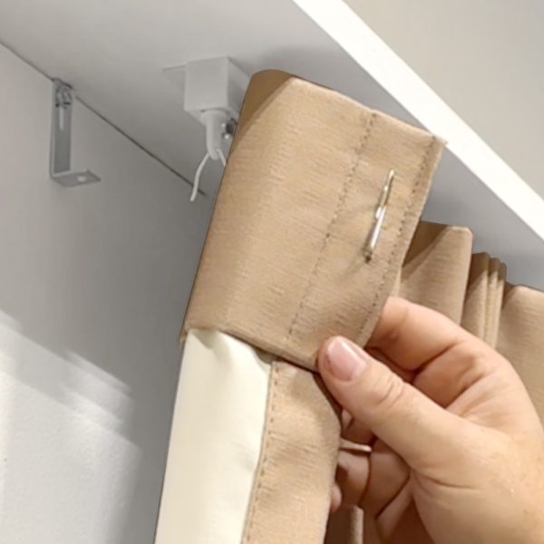 Close up of a drapery with a Fabtex stainless steel drapery pin. The drapery pin is latched on to the carriers along a drapery track.