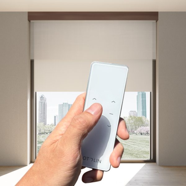Hand clicking on 2-channel, Fabtex handheld remote for roller shade. In the background are blackout & sheer shades.