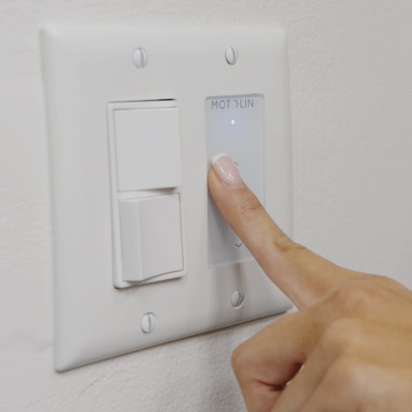 Hand pressing on in-wall, single-channel Fabtex remote for roller shade
