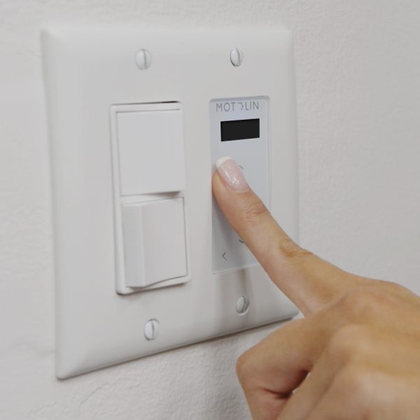 Hand pressing on in-wall, 15-channel Fabtex remote for roller shade